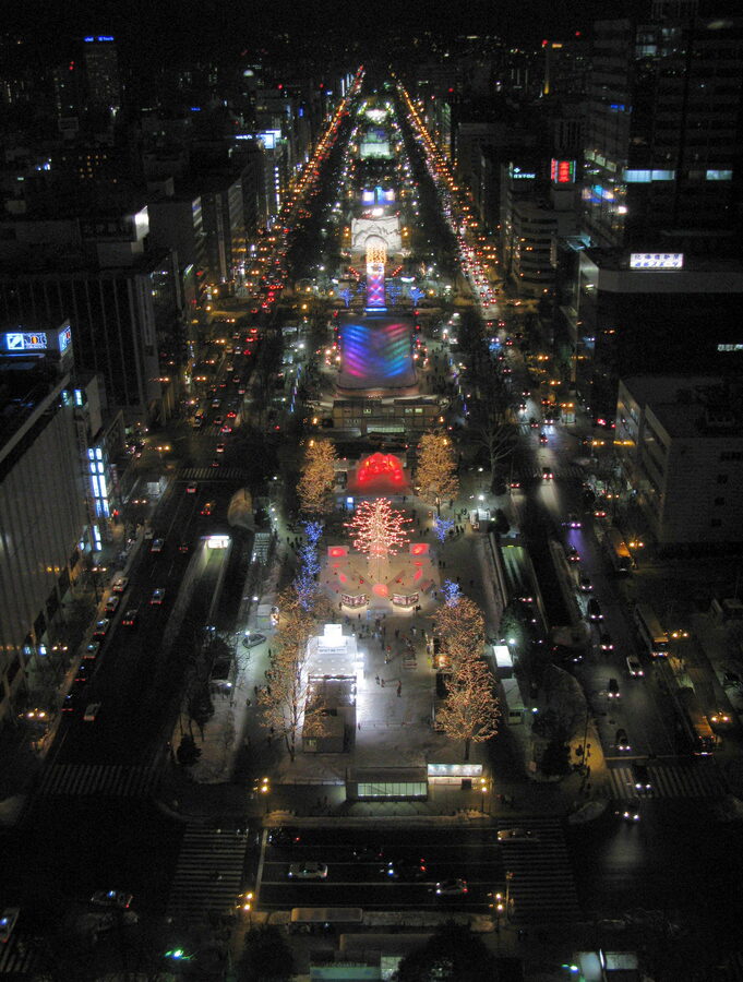 Aerial night panorama of illuminated snow sculptures at Odori Park during Sapporo Snow Festival
