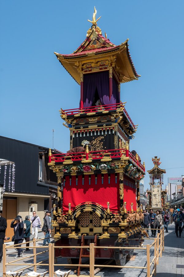Towering Takayama Matsuri yatai float being pulled through Sannomachi street with crowd
