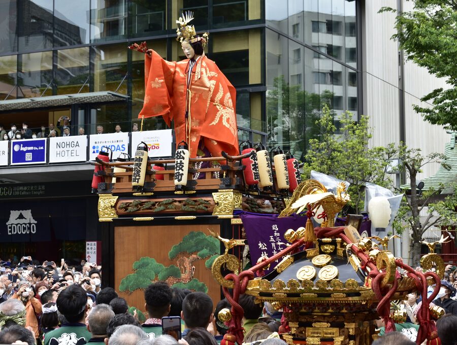 An ornate gold-plated parade float (hoko-gata dashi) on wheels, decorated with mythological figures, photographed during Kanda Matsuri 2023.