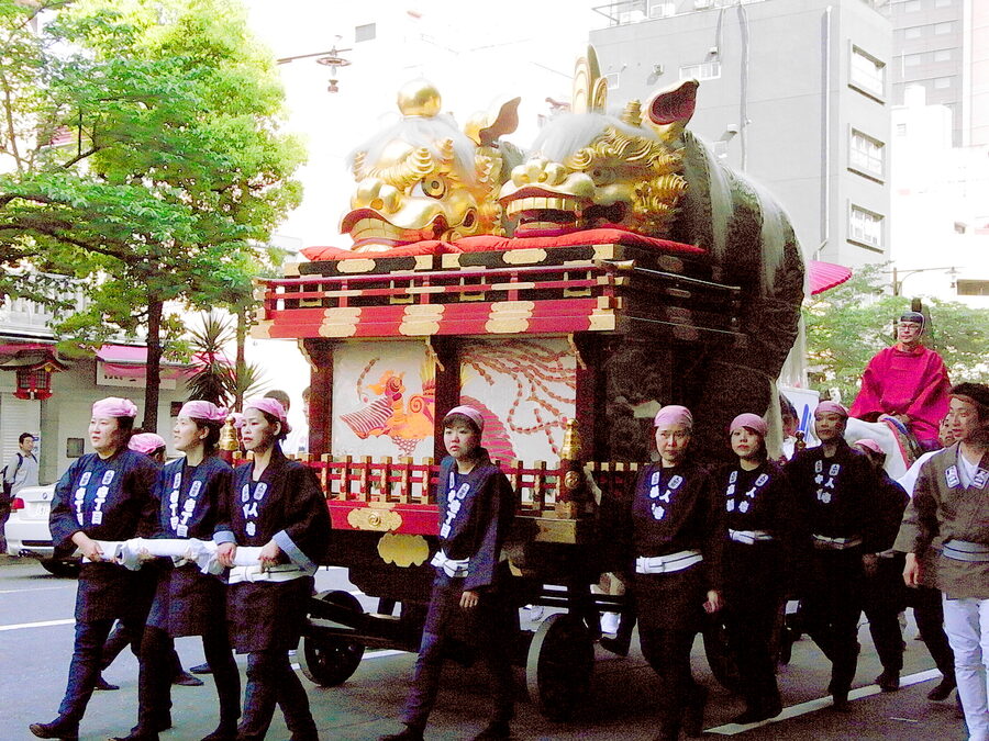 A traditional lion-shaped festival float on wooden wheels at the Kanda Matsuri 2009, with people in happi coats.