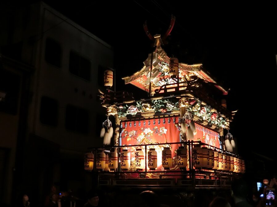 Takayama yomatsuri night yatai procession with rows of paper lanterns glowing on yatai