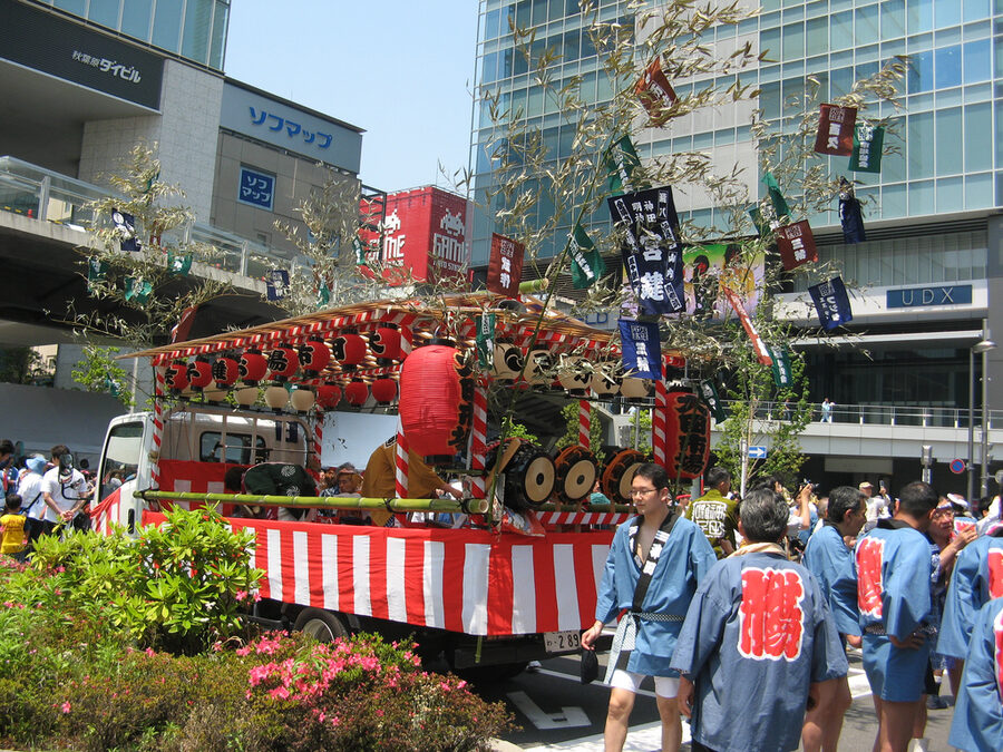 Festival musicians in traditional happi coats playing taiko drums and flutes for the Kanda Matsuri ohayashi music.