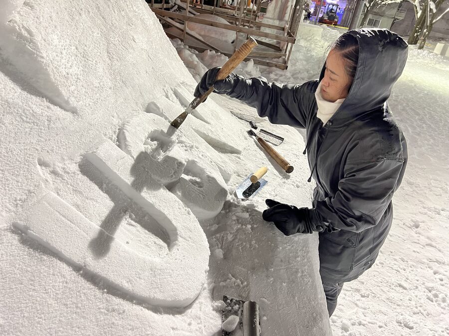 Sailor sculpting an F-35C fighter jet from snow at the 75th Sapporo Snow Festival