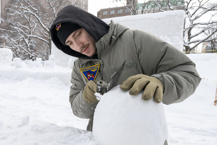 Sculptor refining a snow block surface at the 75th Sapporo Snow Festival 2025
