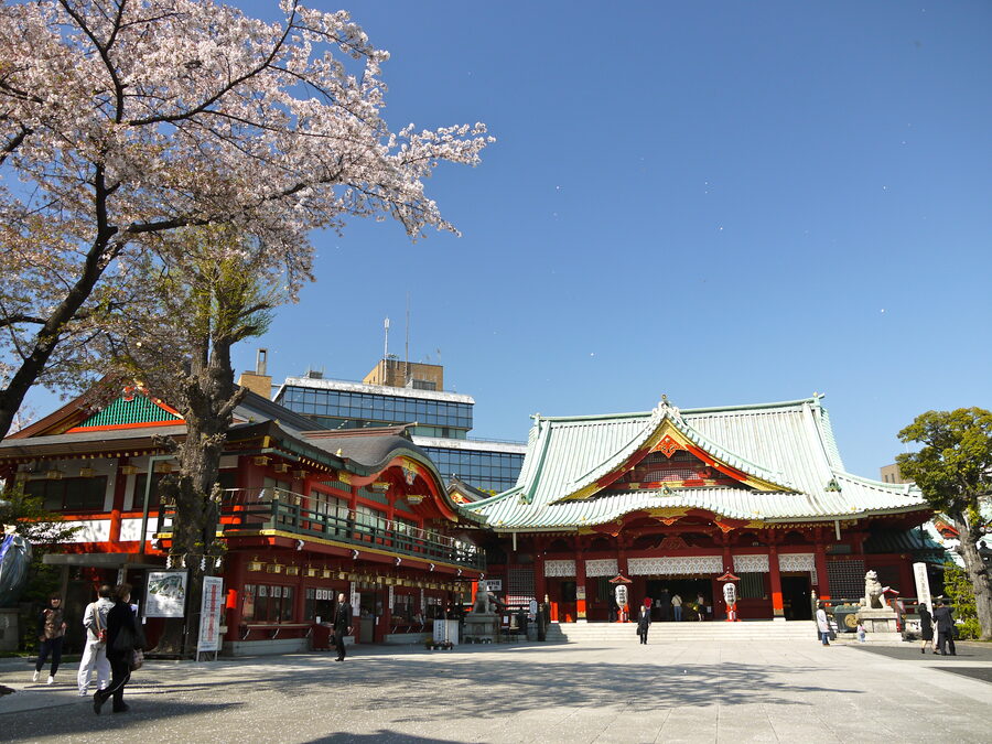 Cherry blossoms in front of a vermilion shrine building at Kanda Myojin.