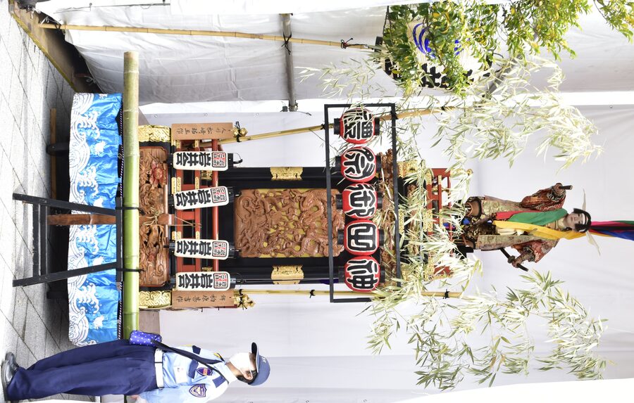 A close-up shot of an ornately decorated Kanda Matsuri parade float passing through Tokyo streets in 2023, showing crowds of onlookers.