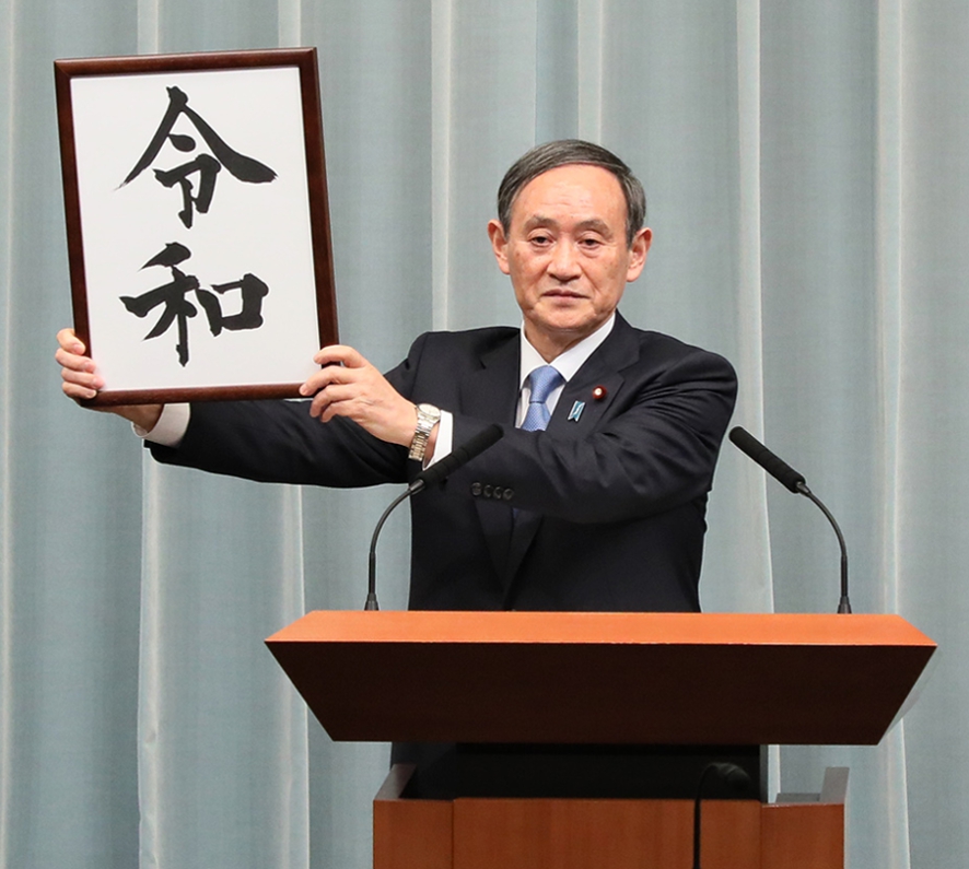 Yoshihide Suga holding the Reiwa calligraphy at the new era name announcement on 1 April 2019