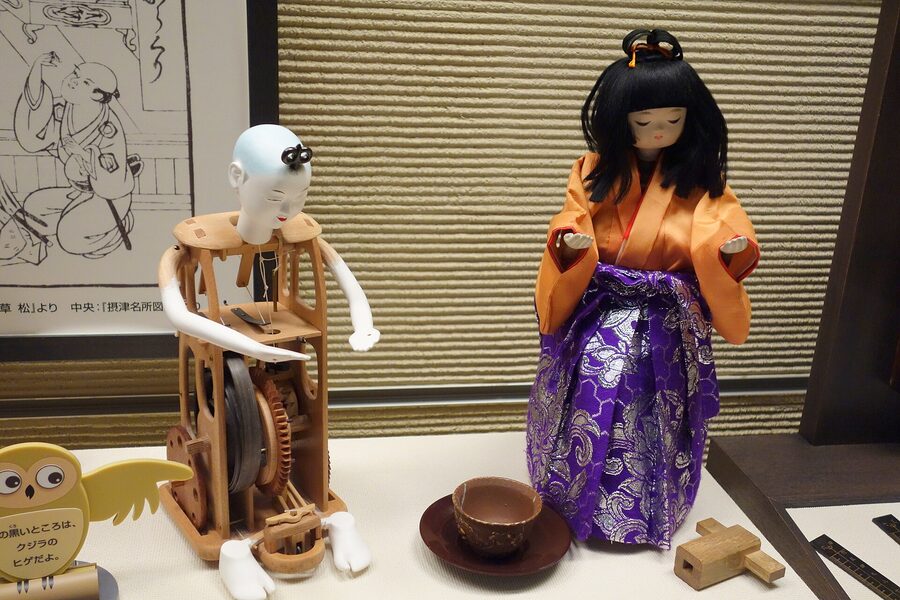 Replica tea-carrying karakuri zashiki doll showing internal cam and spring mechanism