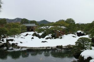The Adachi garden framed as a living painting through a sliding window in winter