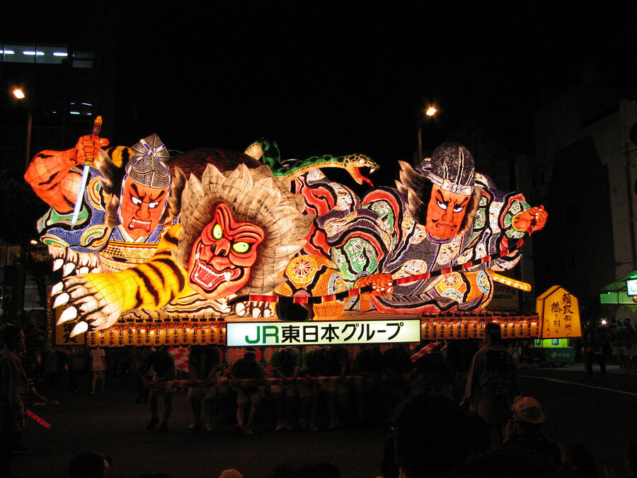 A heavily armoured warrior Nebuta lit from within, red and gold dominating the colour palette.
