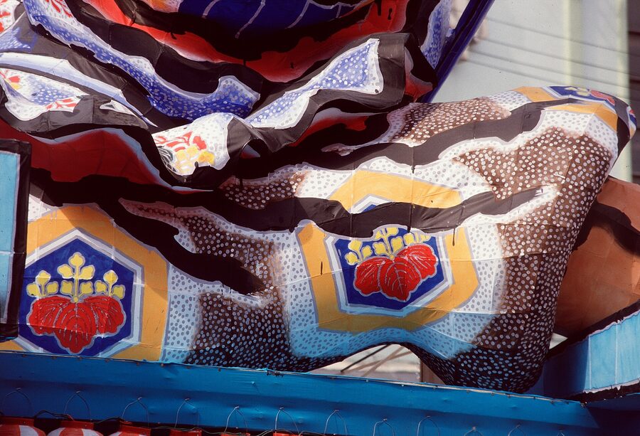 A tableau float showing three figures in dynamic combat, washi paper lit from inside.