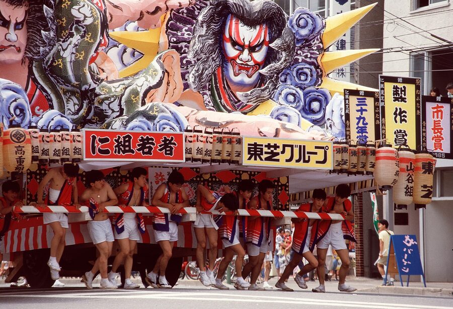 A solid wave of haneto in matching kasa hats jumps in the wake of a passing Nebuta.