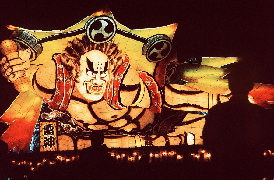 A Nebuta in dominant blues and reds depicts a mythological scene, brush detail clear at close range.