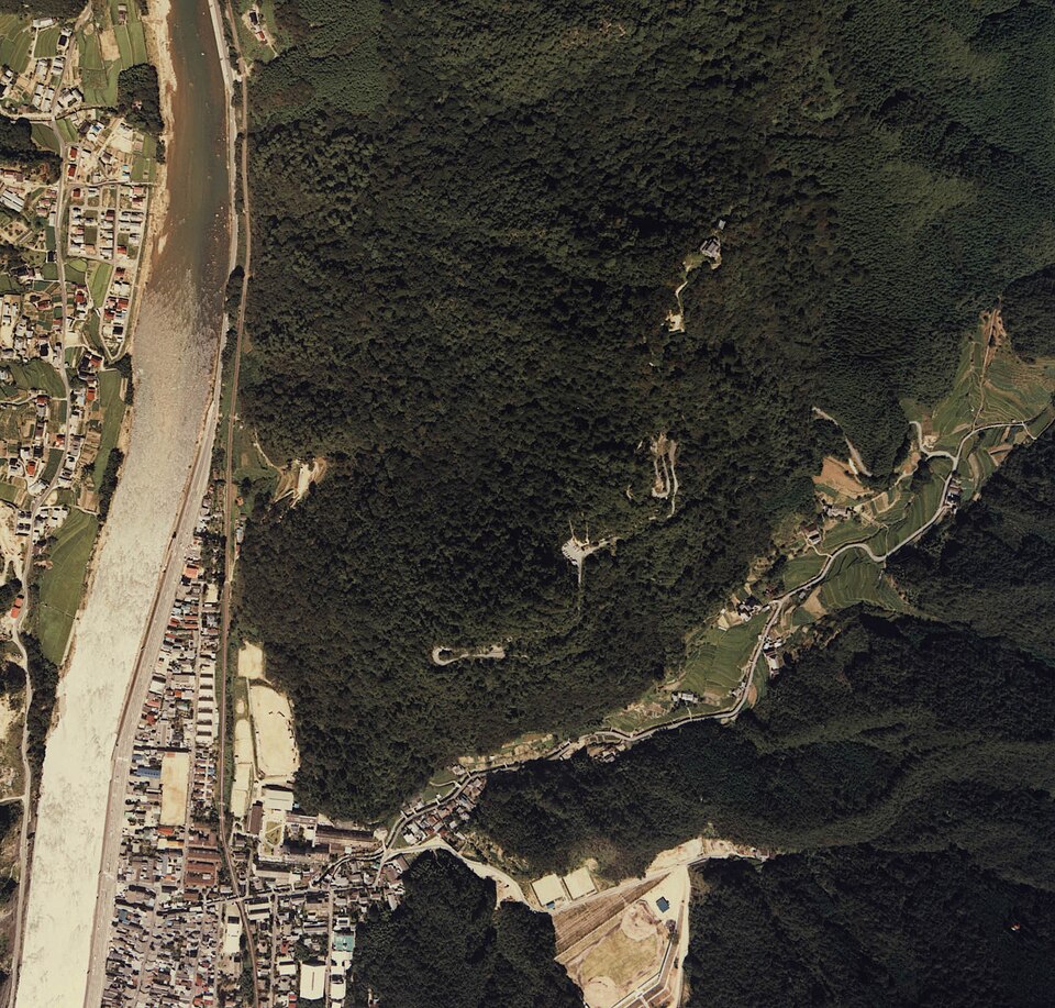 Bitchu Matsuyama Castle aerial view showing the tenshu and honmaru complex on Mount Gagyu with the Takahashi River valley far below