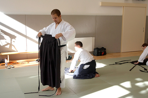 Aikido student folding a hakama after training, the meditative end-of-class ritual