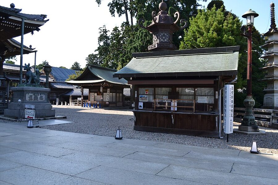 Paired weathered stone foxes with scarves at Toyokawa Inari