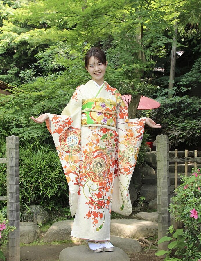 Young Japanese woman in bright pink floral furisode with long hanging sleeves at Coming-of-Age Day seijinshiki ceremony