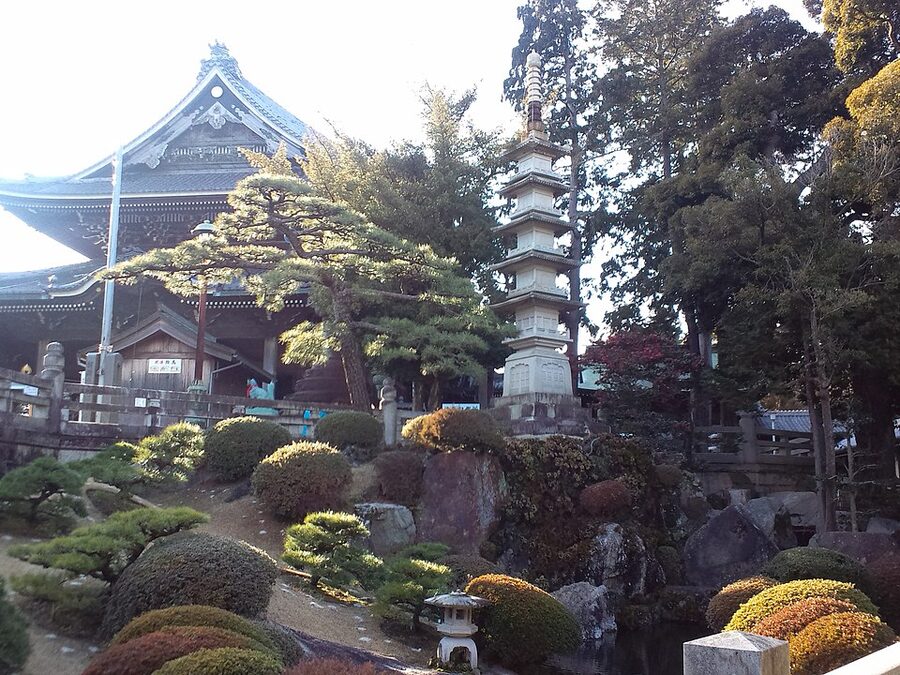 Temple garden at Toyokawa Inari Myogon-ji with raked pond and trimmed shrubs