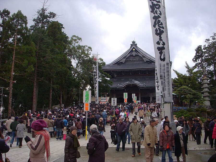 Entrance to Toyokawa Inari during New Year visit with crowds passing through the red torii