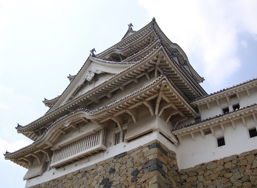 Eaves and onigawara demon-face ridge tiles at Himeji Castle, close-up of the white-plastered architectural detail