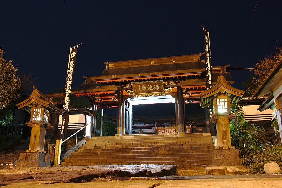 The main Nio gate of Honmyoji Temple illuminated at night during a summer festival in Kumamoto