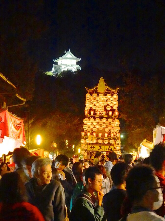 Inuyama Matsuri yamaboko parade float illuminated at night with the castle keep visible behind