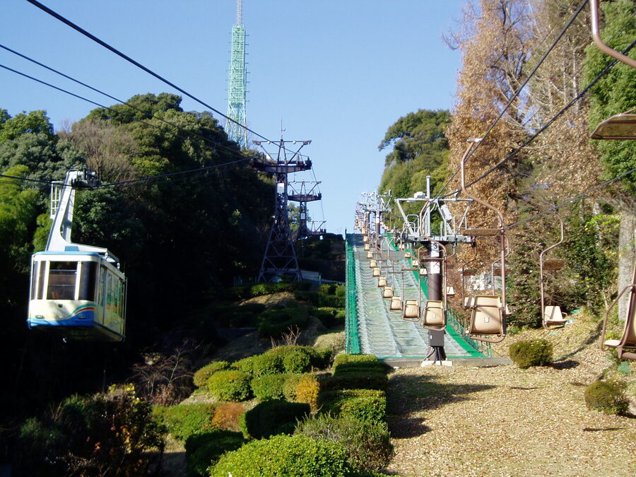 Iyo-Matsuyama Castle ropeway cabin and parallel chairlift ascending Mt Katsuyama with the main keep visible above the cedars