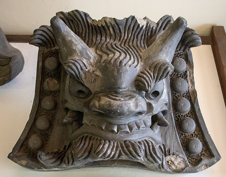Early Meiji-period onigawara demon-face ridge tile from Ritsurin Garden showing evolution from Edo forms