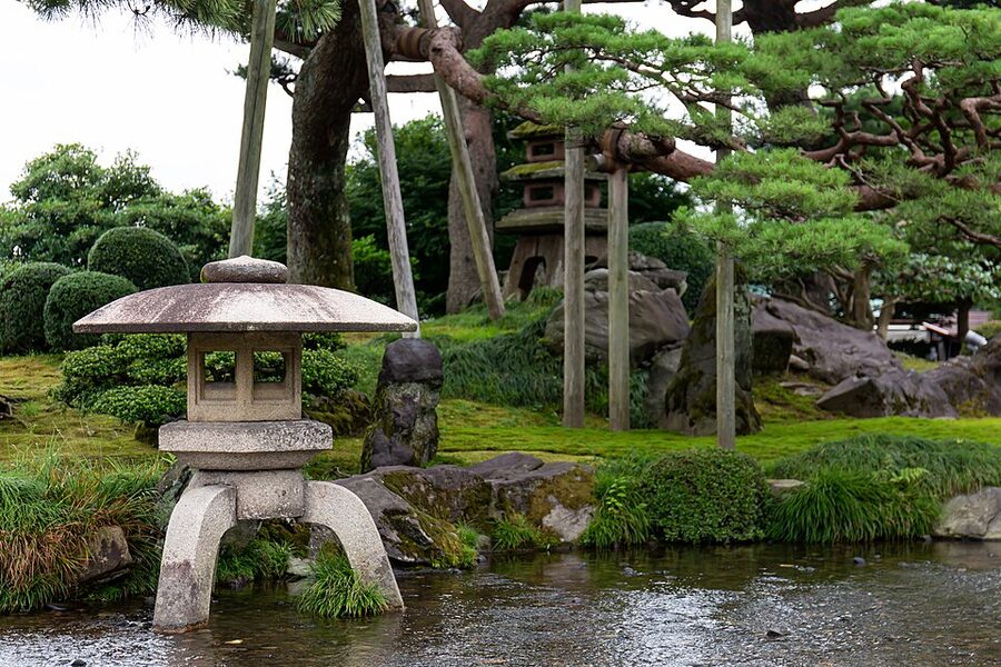 Kasumi Pond at Kenrokuen with stone lanterns and summer green pine trees reflected in still water
