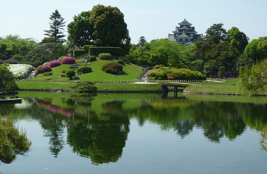Wide lawn expanse and thatched tea pavilion at Korakuen in Okayama in summer