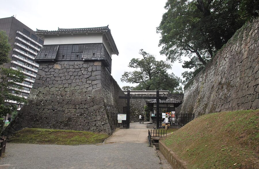 Curved musha-gaeshi stone wall at Kumamoto Castle with gentle angle at bottom steepening to near vertical with overhanging upper stones