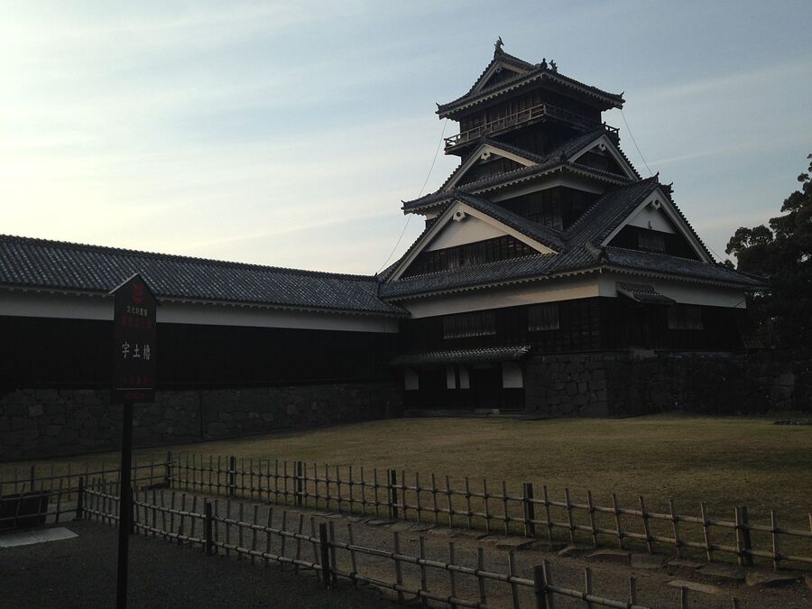 Uto Yagura at Kumamoto Castle photographed at dusk showing the surviving 1607 wooden structure lit against a blue evening sky