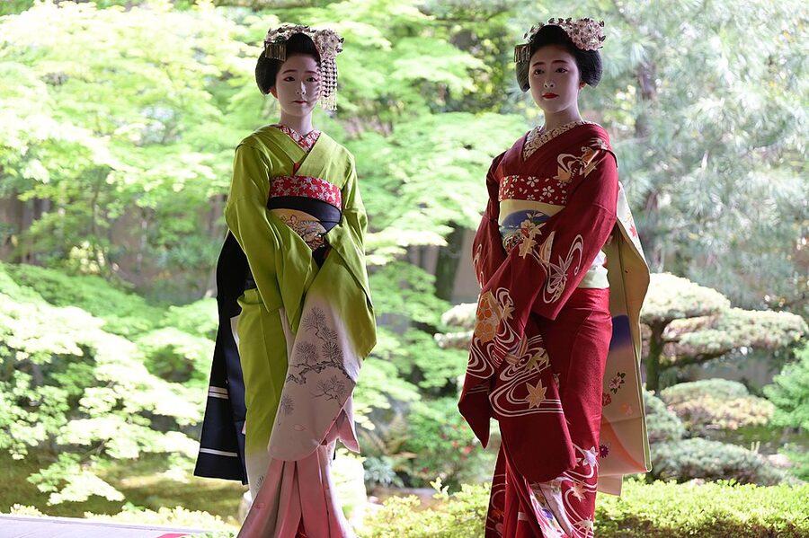 Two young maiko apprentice geisha in Kyoto wearing brightly patterned kimono with trailing darari obi at Seirai-in Temple