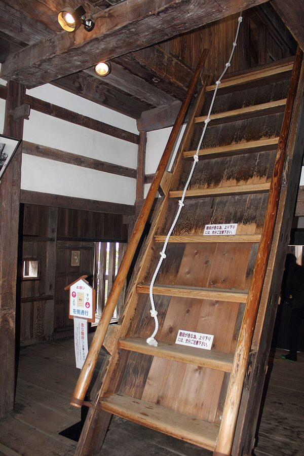 Interior of Maruoka Castle tenshu showing the extremely steep wooden staircase between floors with guide rope