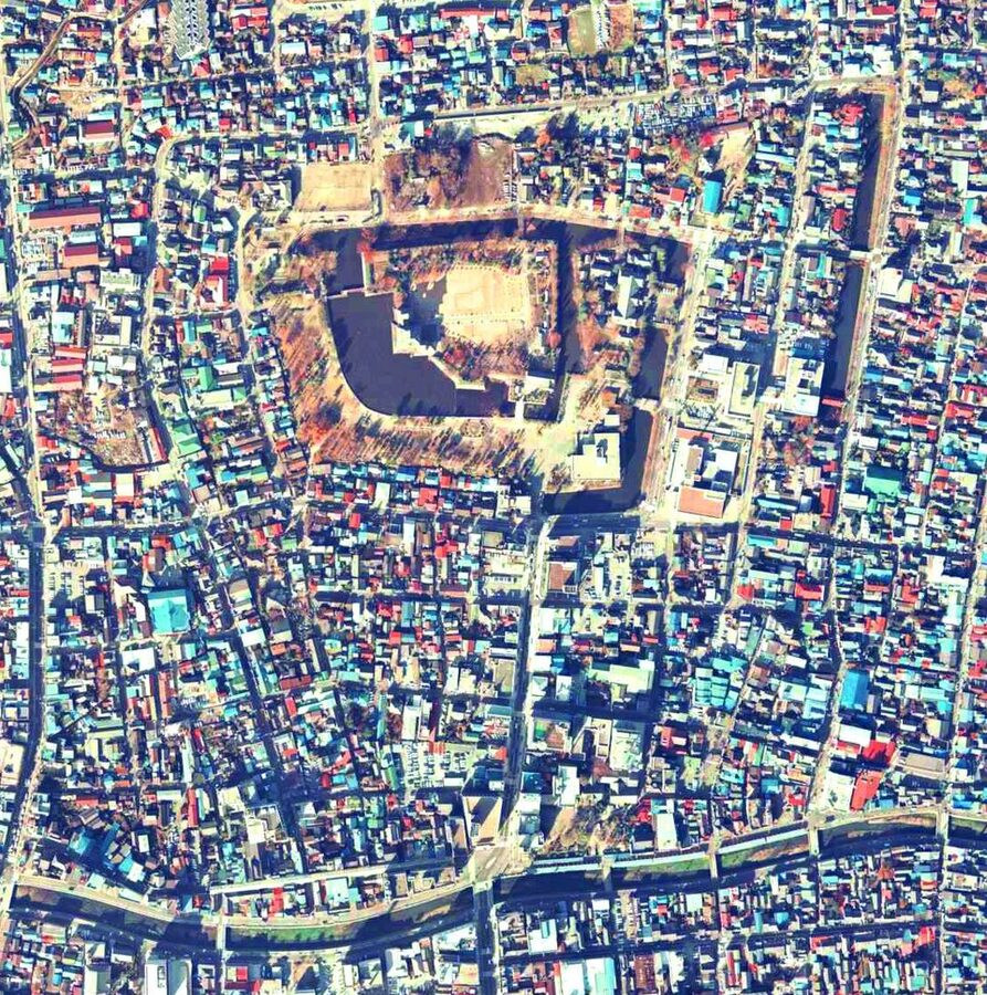 Aerial photograph of Matsumoto Castle from 1975 showing the full moat ring system surrounding the central keep complex and the grid of the Matsumoto castle town