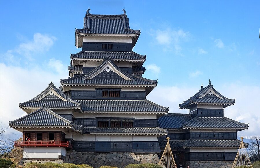 Stitched panorama of Matsumoto Castle showing the keep complex and the Northern Japanese Alps visible in the distant background