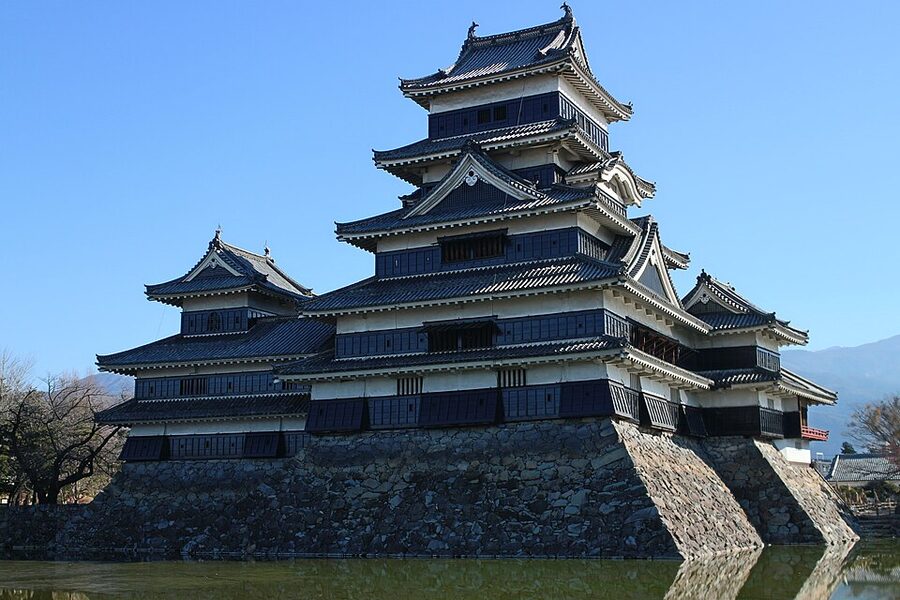 Matsumoto Castle daitenshu viewed from the eastern approach with winter light raking across the stone base and the black lacquered upper floors