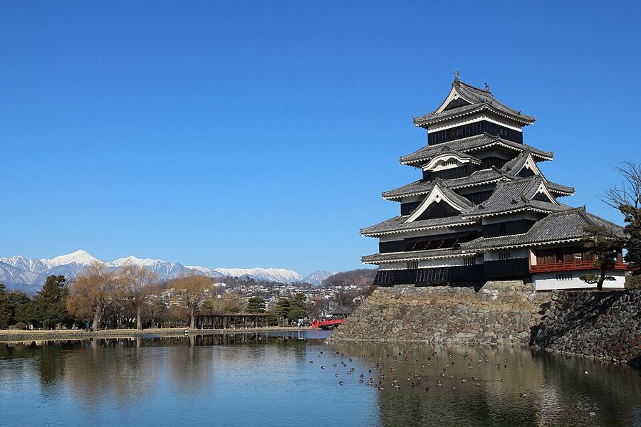 Matsumoto Castle in February 2017 with snow-covered ground framing the black keep complex and leafless cherry trees along the inner moat edge