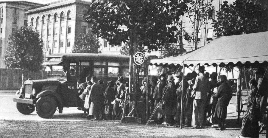 Black-and-white photograph of a Mitsukoshi department store courtesy bus parked at Tokyo Station around 1932