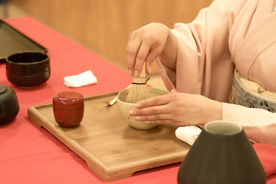 Modern practitioner whisking matcha in formal tea ceremony dress at a Japanese cultural festival