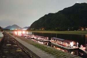 Long-exposure photograph of ukai cormorant fishing boats with burning kagaribi torches drifting down the Nagara River beneath Gifu Castle at night
