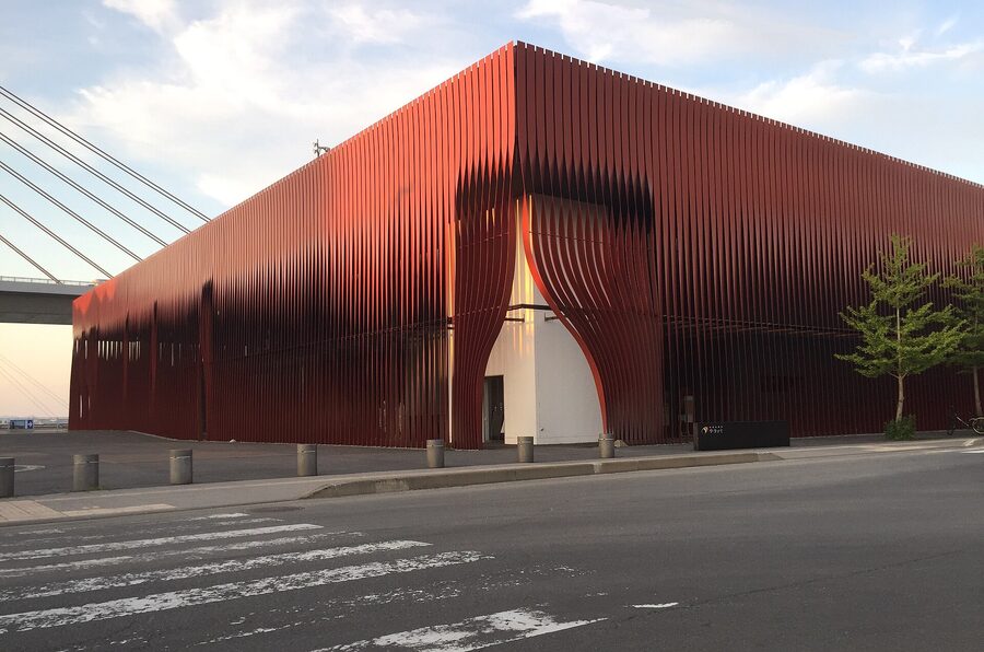 The red vertical steel ribbons of Wa Rasse next to JR Aomori Station are designed to evoke beech-forest light.