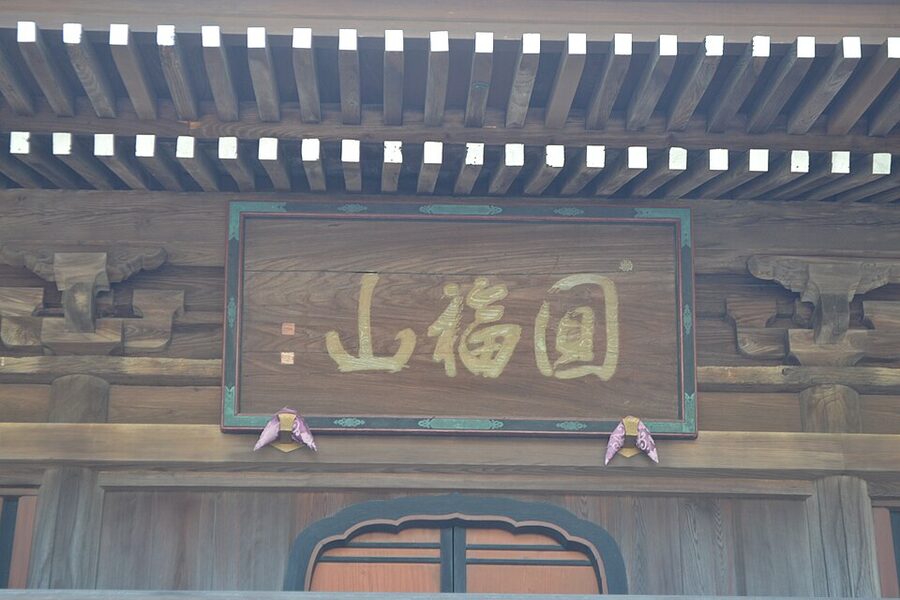 Precinct walkway inside Toyokawa Inari lined with stone lanterns and trees