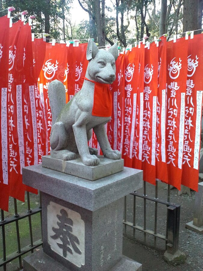 Single upright fox statue holding a scroll at Reiko-zuka