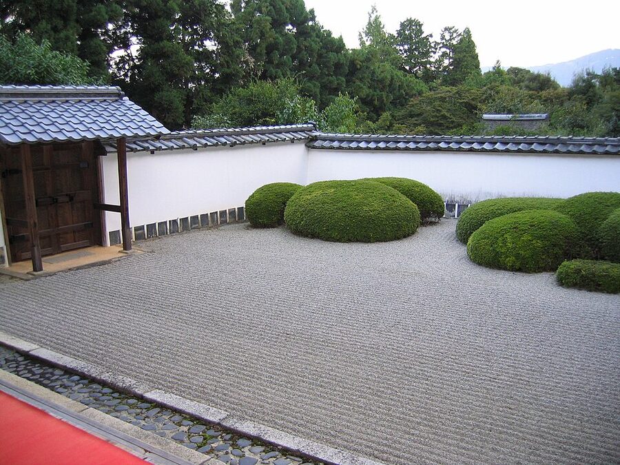 Clipped azalea groupings at Shoden-ji with Mount Hiei framed above the garden wall as shakkei