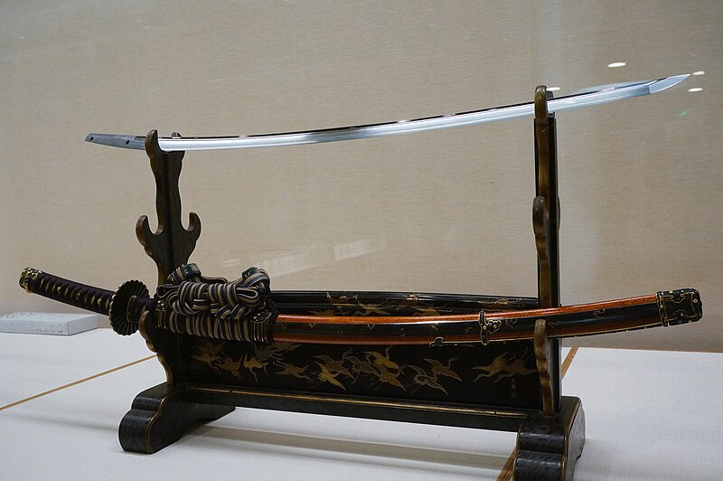 A curved tachi sword by Osafune Kanemitsu of the Bizen school laid flat with blade uppermost showing the sweeping curve for mounted combat