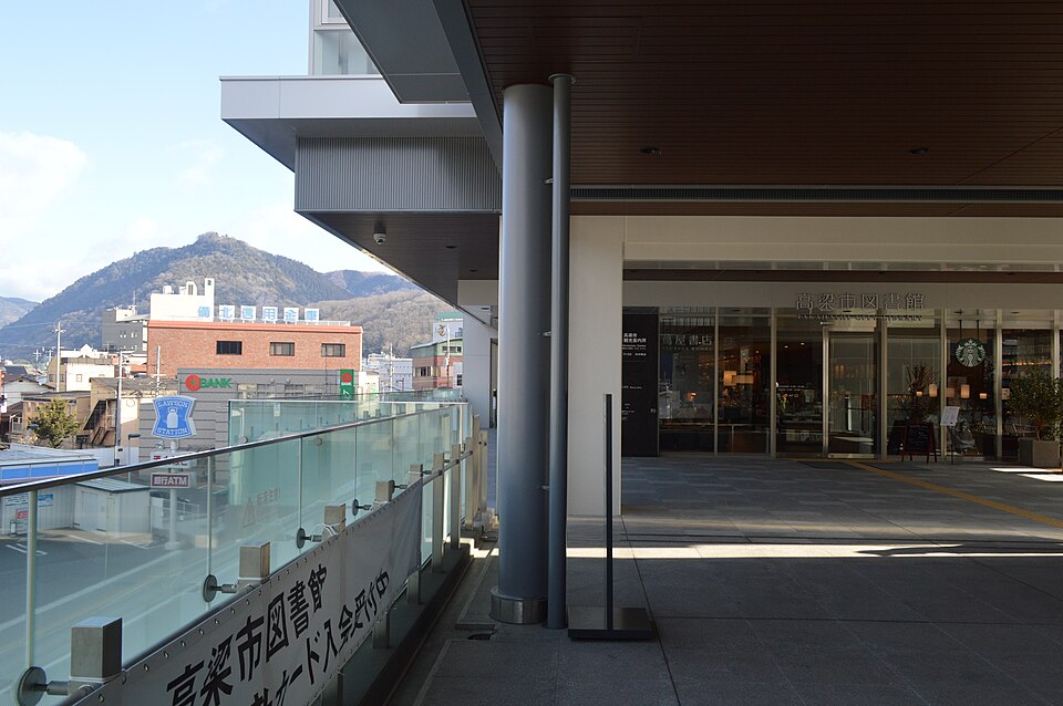 Takahashi City Library modernist building in central Takahashi city with Bitchu Matsuyama Castle visible on the mountain ridge above in the distance