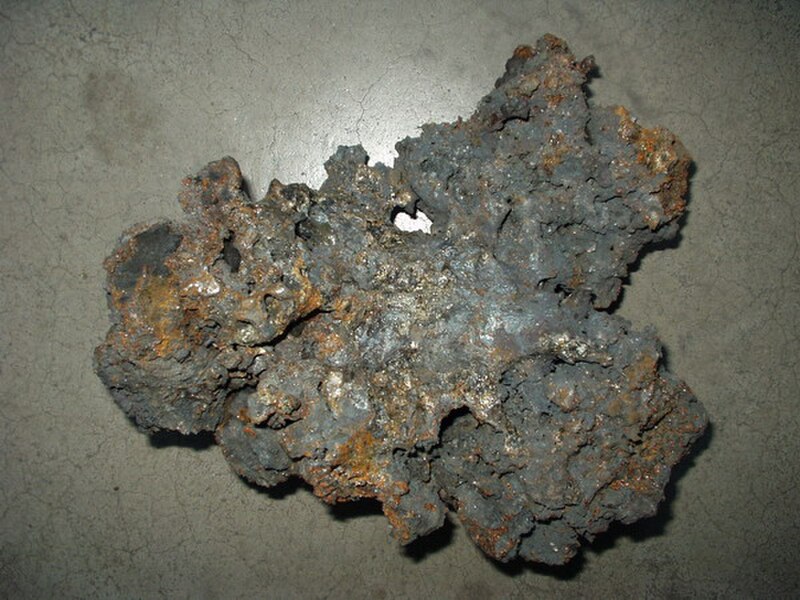 Rough angular lumps of tamahagane steel fresh out of a tatara smelting furnace, varying in colour from pale grey to dark blue-black with crystalline fractures