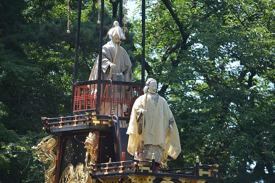 Life-size Takasago Noh-play doll in costume displayed on a sharakubune morning boat at the Owari Tsushima Tenno Matsuri, facing the shrine