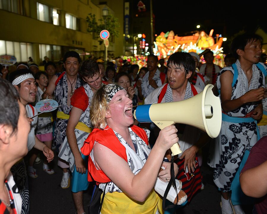 Sailors from the USS Fitzgerald in haneto costume march beside an Aomori Nebuta float in 2013.